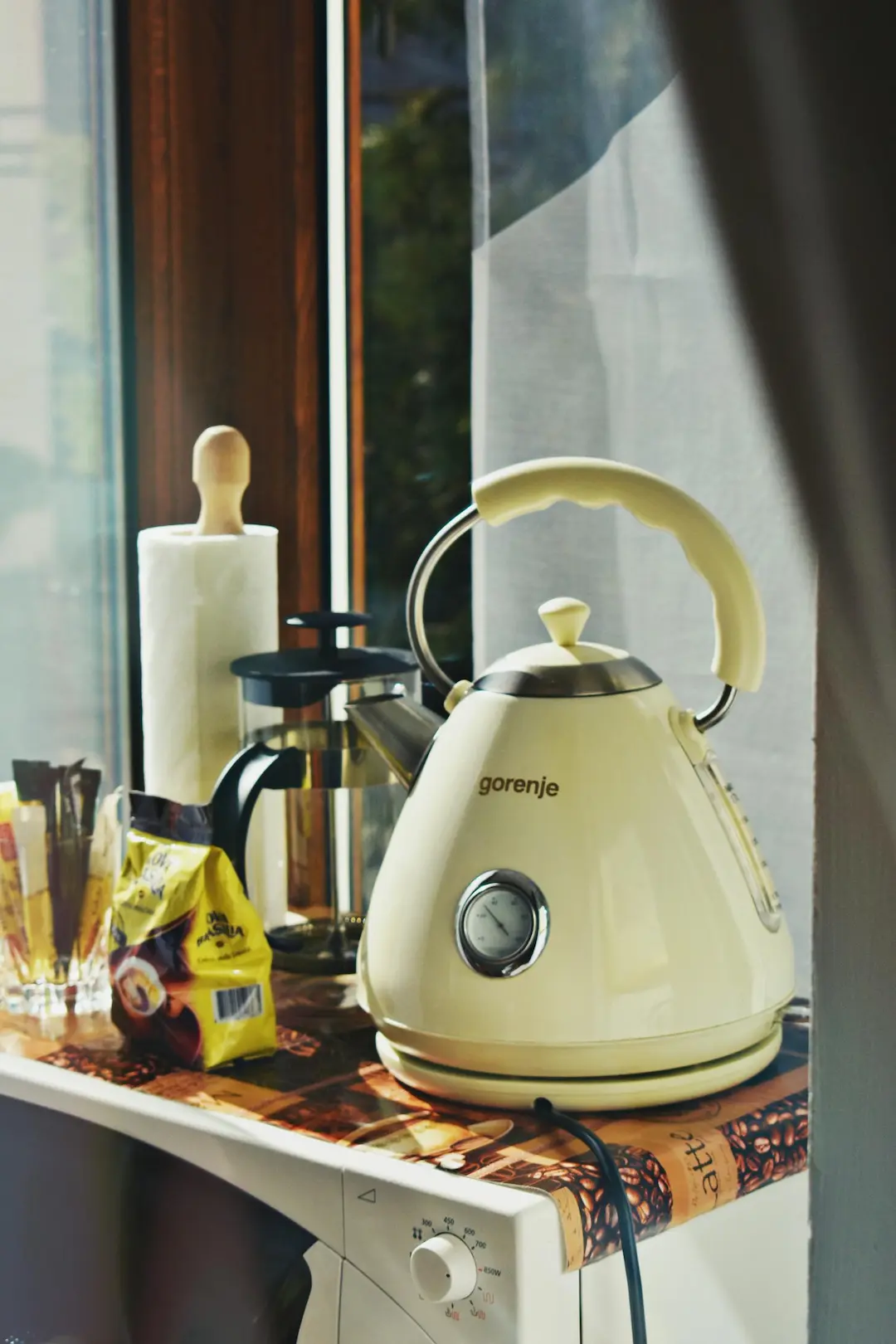 A retro style electric kettle on a kitchen counter with coffee accessories, creating a cozy indoor atmosphere.